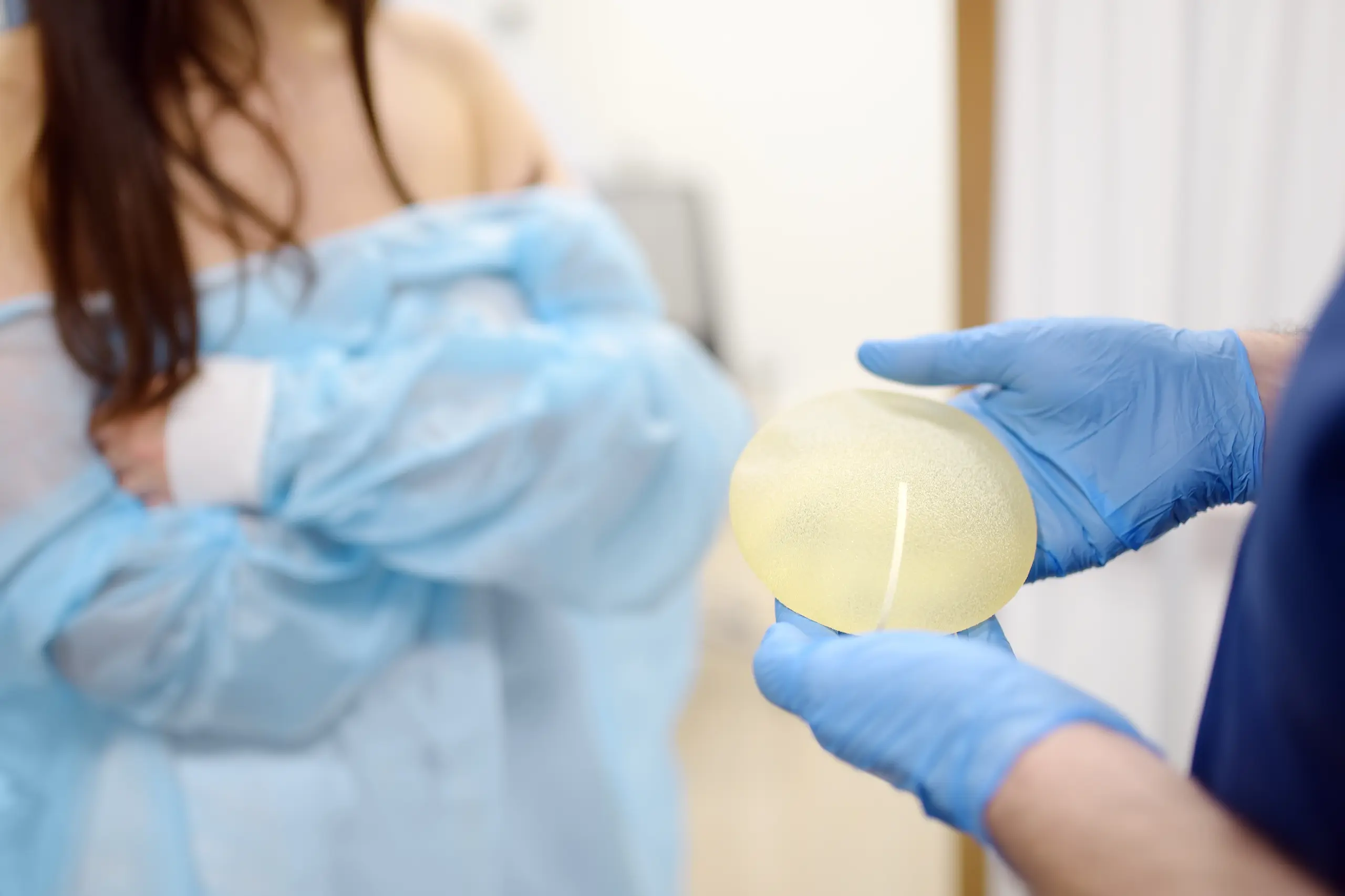 Surgeon showing a silicone breast implant to a patient