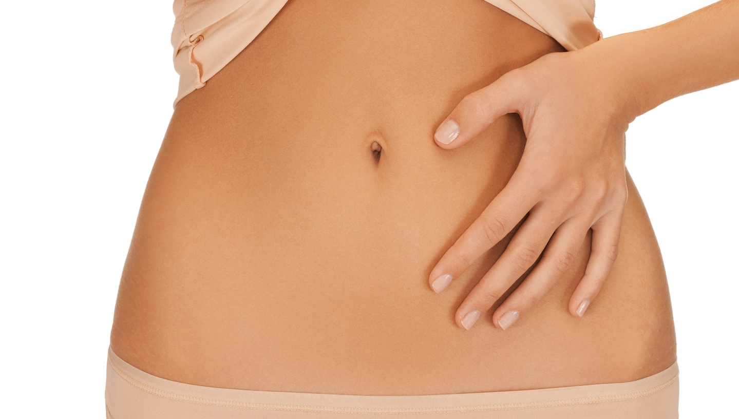 close up of a woman feeling her waiste with her hand after tummy tuck